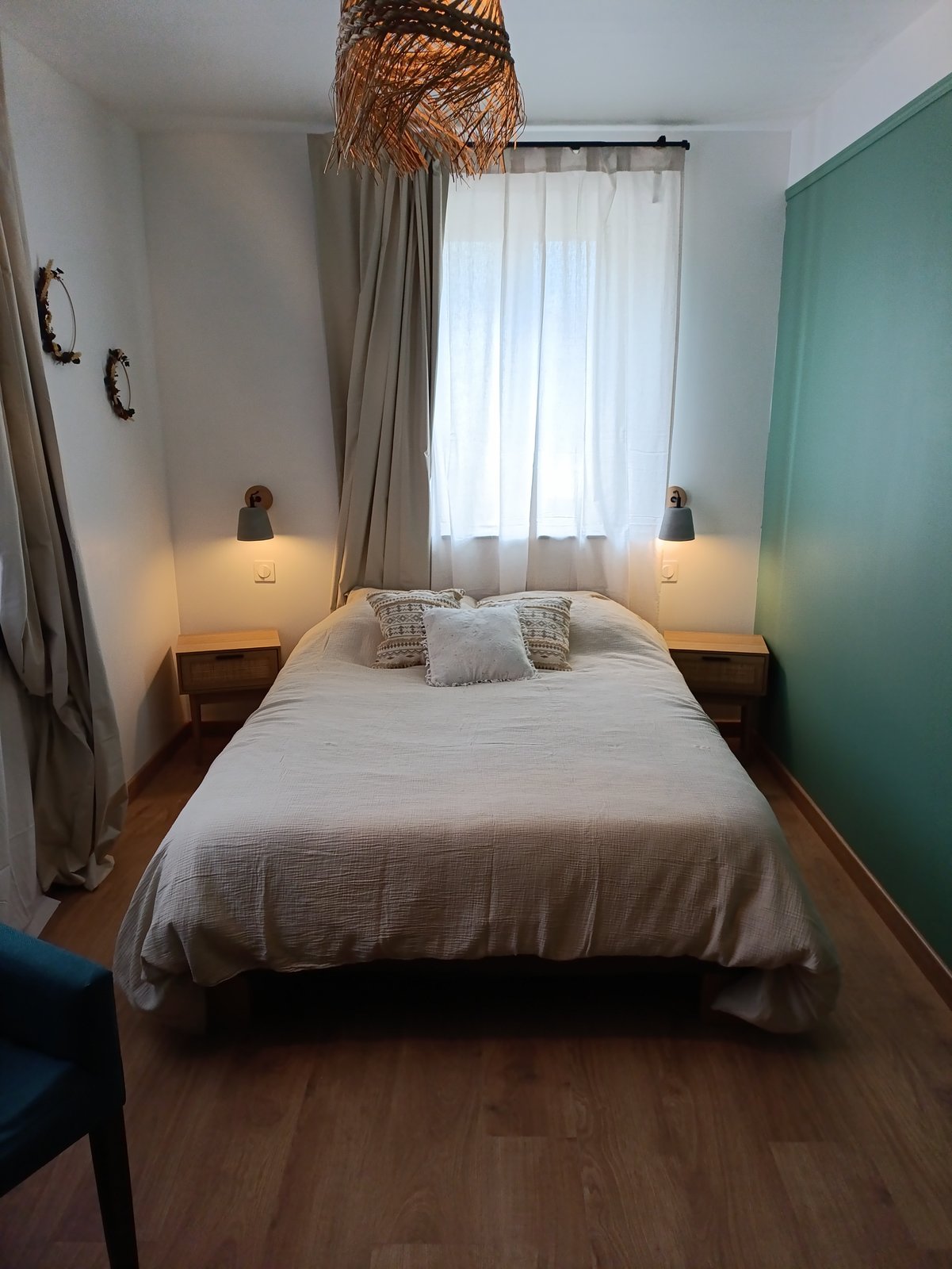 Chambre 1, lit double avec tête de lit en tissu beige et mur vert d'eau
